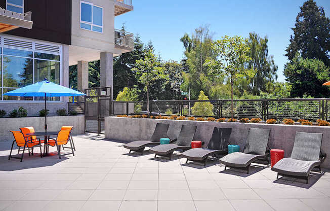 A patio with chairs and a table with a blue umbrella. at Kirkland Crossing Apartments, Kirkland, Washington