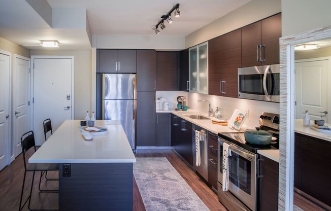 a kitchen with dark wood cabinets and white countertops at The Acadia at Metropolitan Park, Arlington, VA, 22202