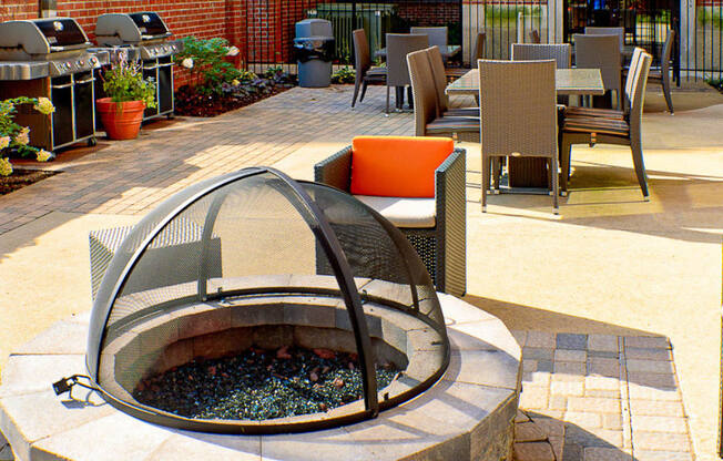 a fire pit on a patio with chairs and tables