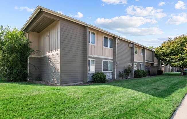 an apartment building with a green lawn and a sidewalk