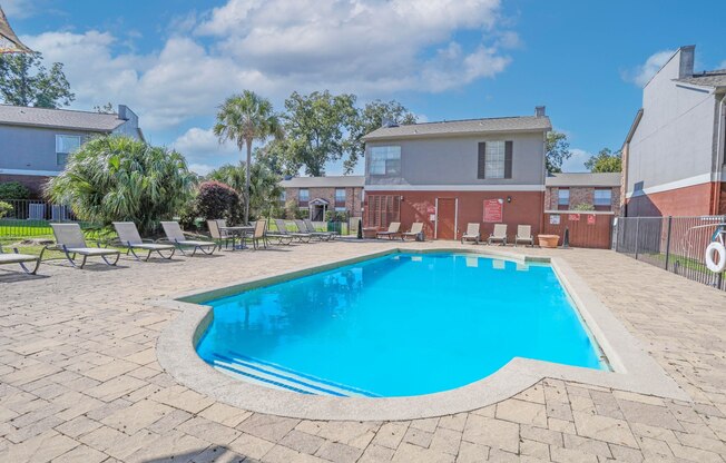 A fenced pool surrounded by a brick patio and chairs at Magnolia Apartments in Shreveport, LA