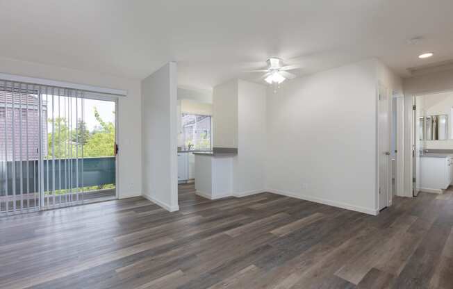 an empty living room with a large window and a ceiling fan