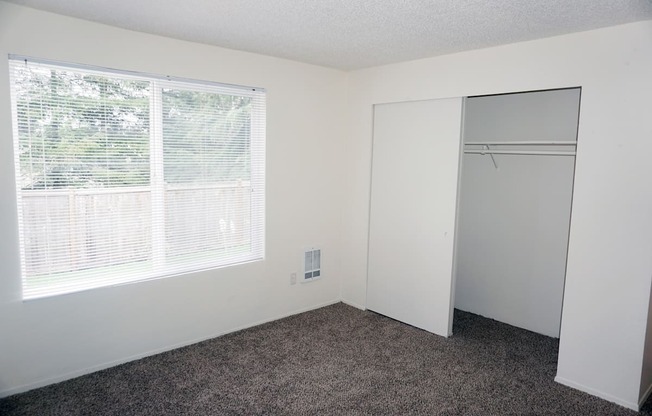 an empty bedroom with a large window and a closet