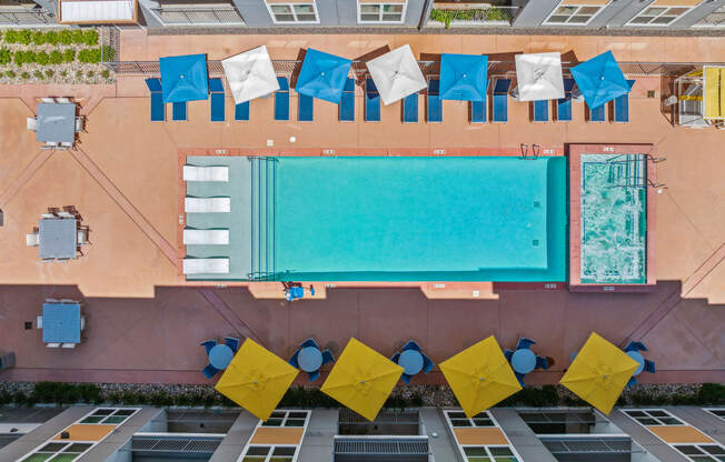 a birds eye view of a building with a pool and blue and yellow tables and chairs