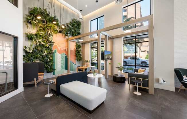 a lobby with couches and chairs and a wall of plants