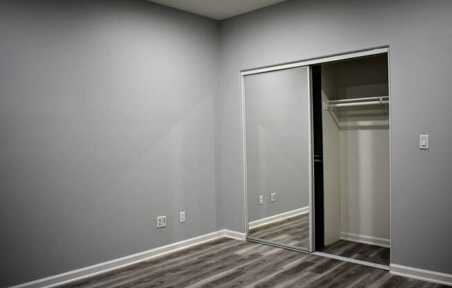 View of bedroom with wood look flooring with sliding glass door into closet