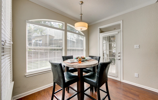 View of Upgraded Apartment Interior, Showing Dining Area with Dining Table, Chairs, and Window View at Stonebriar of Frisco Apartments