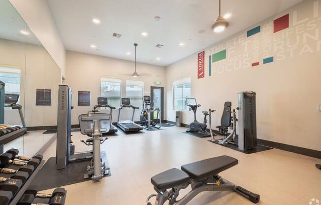 a gym with cardio machines and weights on the floor and a wall of windows