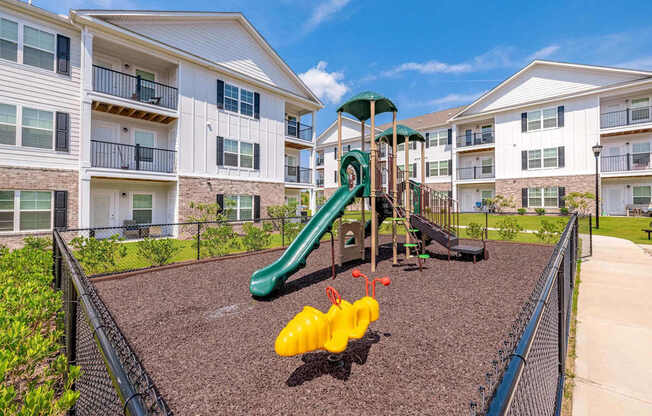 Playground with slide in fenced-in area with mulch