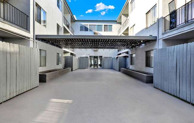 A long, narrow courtyard between two buildings with a metal roof.