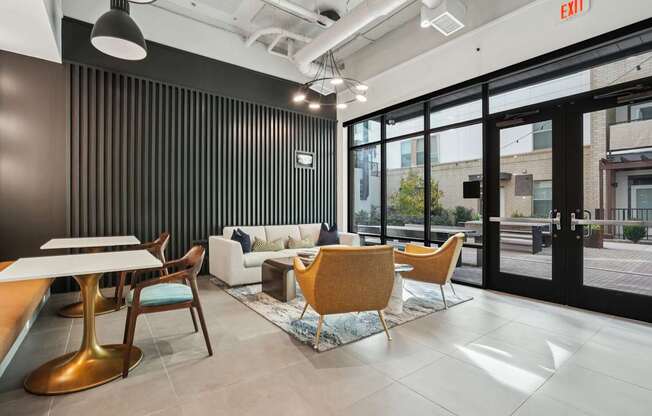 A modern office space with a black vertical blind on the wall, a white sofa, a wooden table, and a yellow chair.