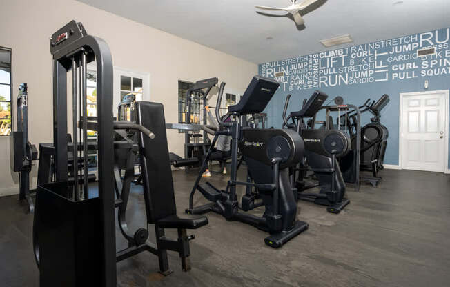 A gym with a variety of equipment including a weight machine, a squat rack, and a treadmill.