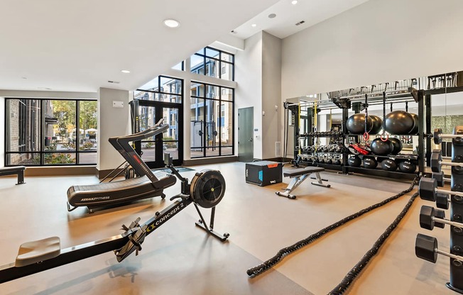 A gym with a rowing machine, dumbbells and weight plates at Preston Ridge Apartments in Cary, NC.