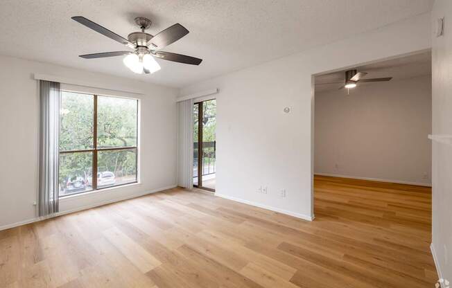 A room with a ceiling fan and wooden flooring.
