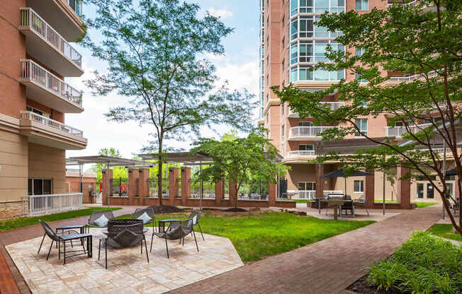 A patio with chairs and a table is surrounded by apartment buildings.