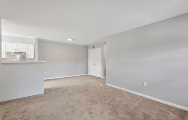 the living room and kitchen of an empty home with carpeting