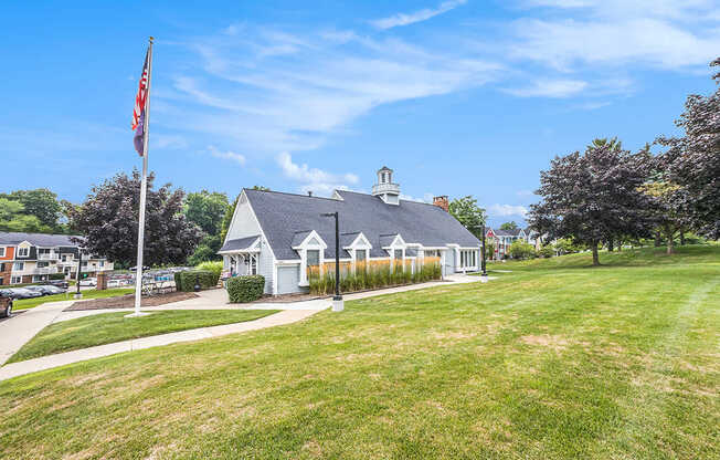 A leasing office with a flag on a pole in front of a green lawn at Apple Ridge Apartments, Michigan, 49534