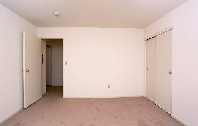 an empty room with white walls and a door to a closet