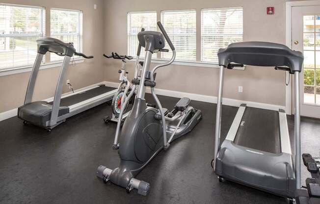 A gym with treadmills, elliptical machines, and a stationary bike.