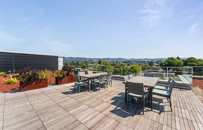 the deck on the roof of a building with tables and chairs