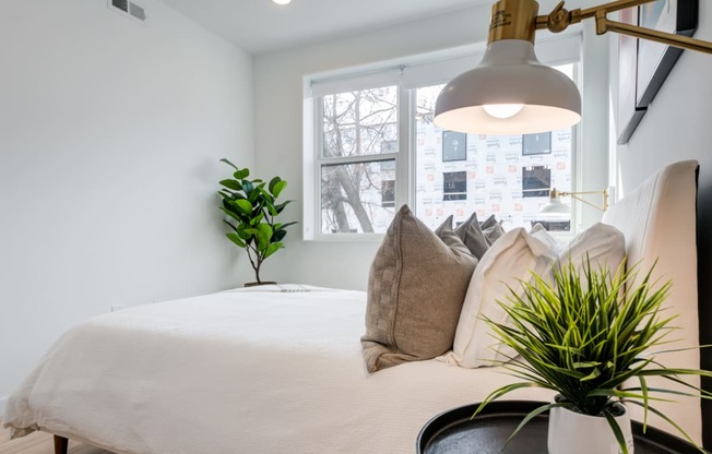 a bedroom with a bed with pillows and a lamp and a window