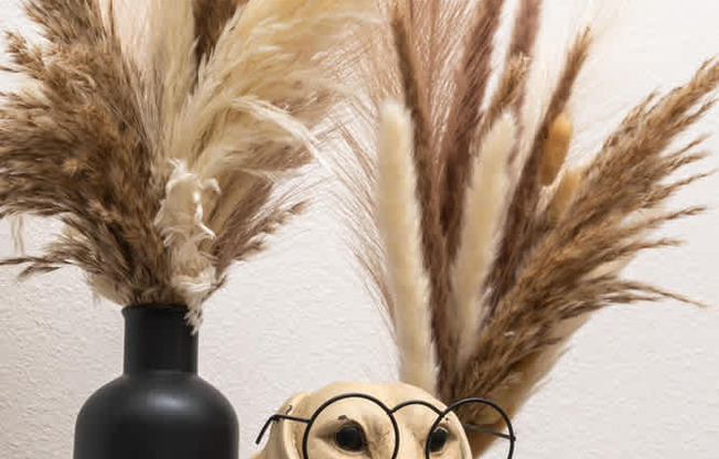 A black vase with a plant in it sits on a table.