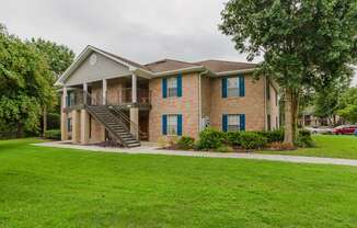 the view of a brick house with a yard and stairs