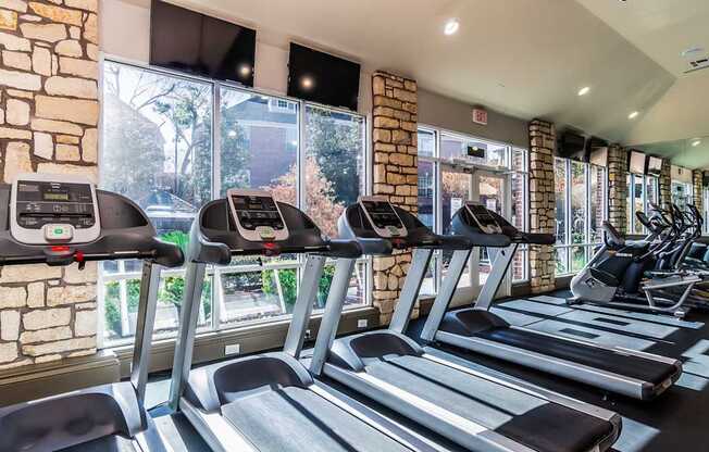 A gym with treadmills and a brick wall.