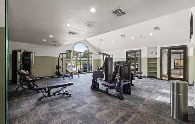 A gym with a variety of equipment including treadmills, weights, and exercise machines.