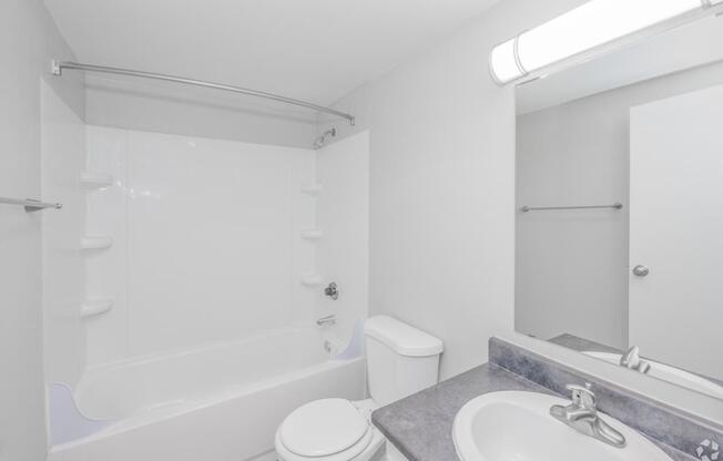 A white bathroom with a toilet, sink, and bathtub.