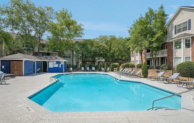 A large swimming pool surrounded by lounge chairs and trees.