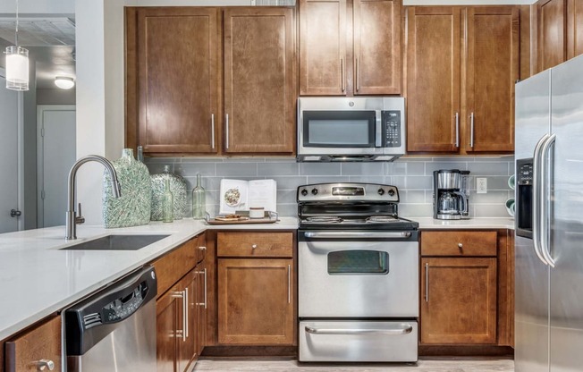 Kitchen with stainless steel appliances and wooden cabinets at The Atlantic Highland Park, Dallas