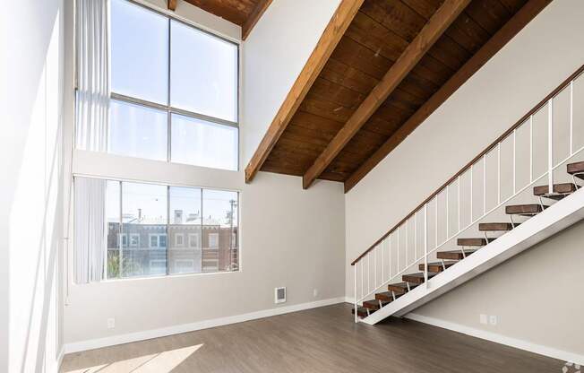 a living room with a staircase and large windows
