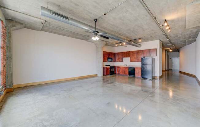 A large, empty room with a concrete floor and ceiling, and a red brick wall on the left side.