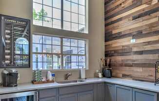 A coffee chart is displayed on a blackboard in a room with a wooden wall and a large window.