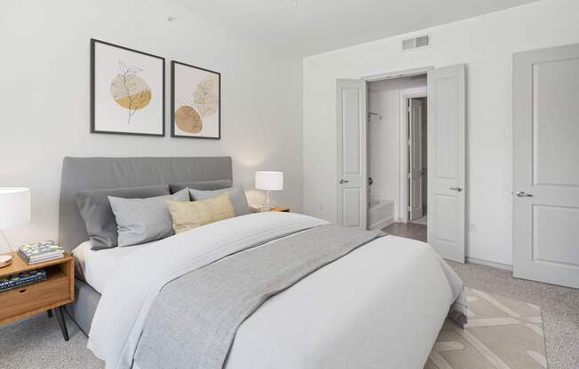 A bedroom with a large bed and two framed pictures on the wall.