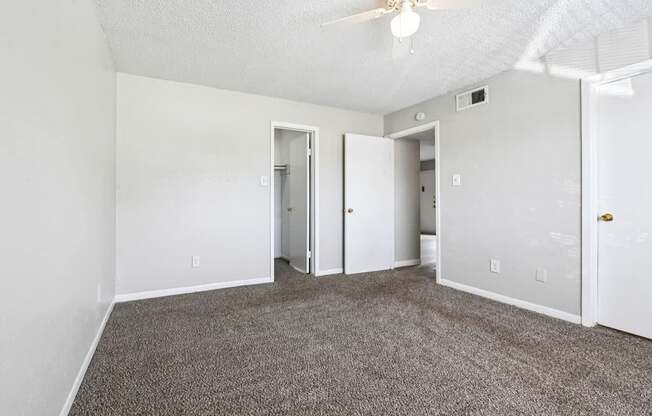 A room with a carpeted floor and a ceiling fan.