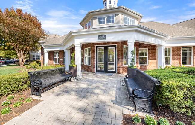 the front porch of a house with two benches and a walkway