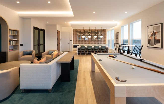 a living room with a pool table and a dining room