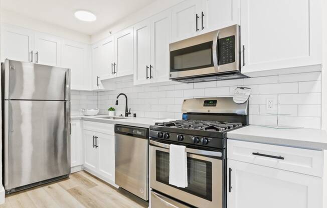 a white kitchen with stainless steel appliances and white cabinets