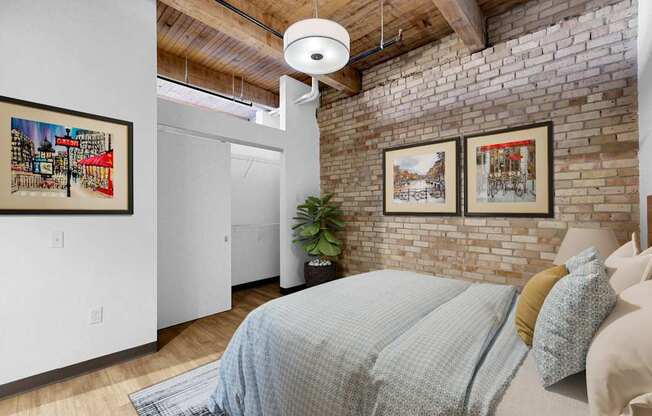 A bedroom with a bed, a plant, and pictures on the wall.