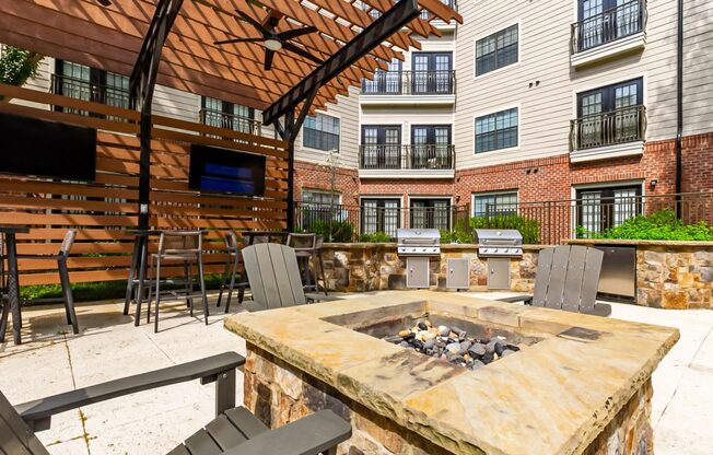 a patio with a fire pit in front of an apartment building