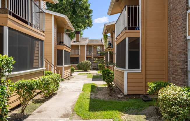 a pathway lined with yellow and brown condominiums