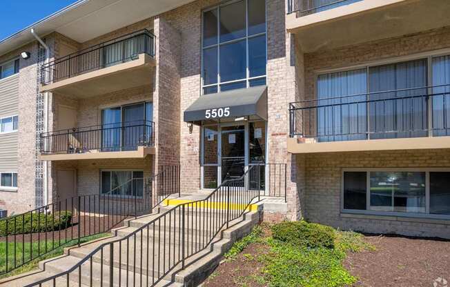 The image shows the front of apartment building number 5505 with a black metal railing on the stairs.