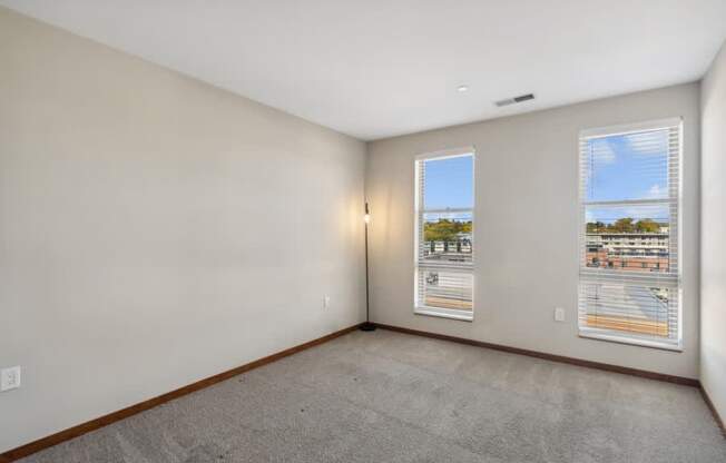the living room of an apartment with two windows and a carpet