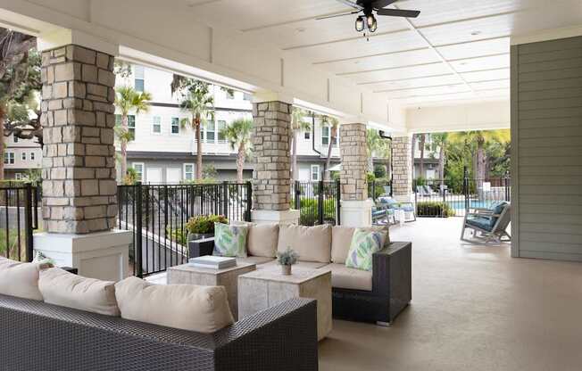 A patio with a black railing and a white ceiling fan.