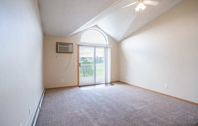 A room with a carpeted floor and a ceiling fan. Bismarck, ND Sierra Ridge Apartments