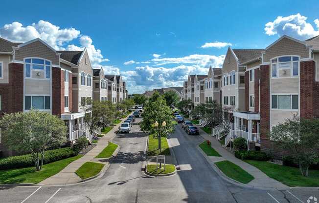 A street view of a residential area with cars parked on the side of the road.