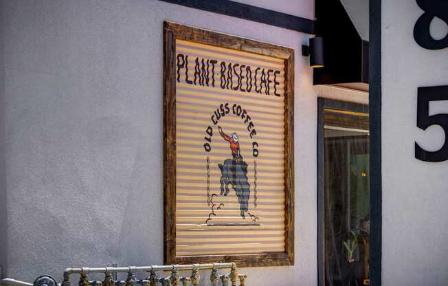 A sign for a plant-based cafe is hanging on a wall.