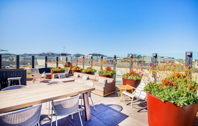 A patio with a table, chairs, and potted plants.
